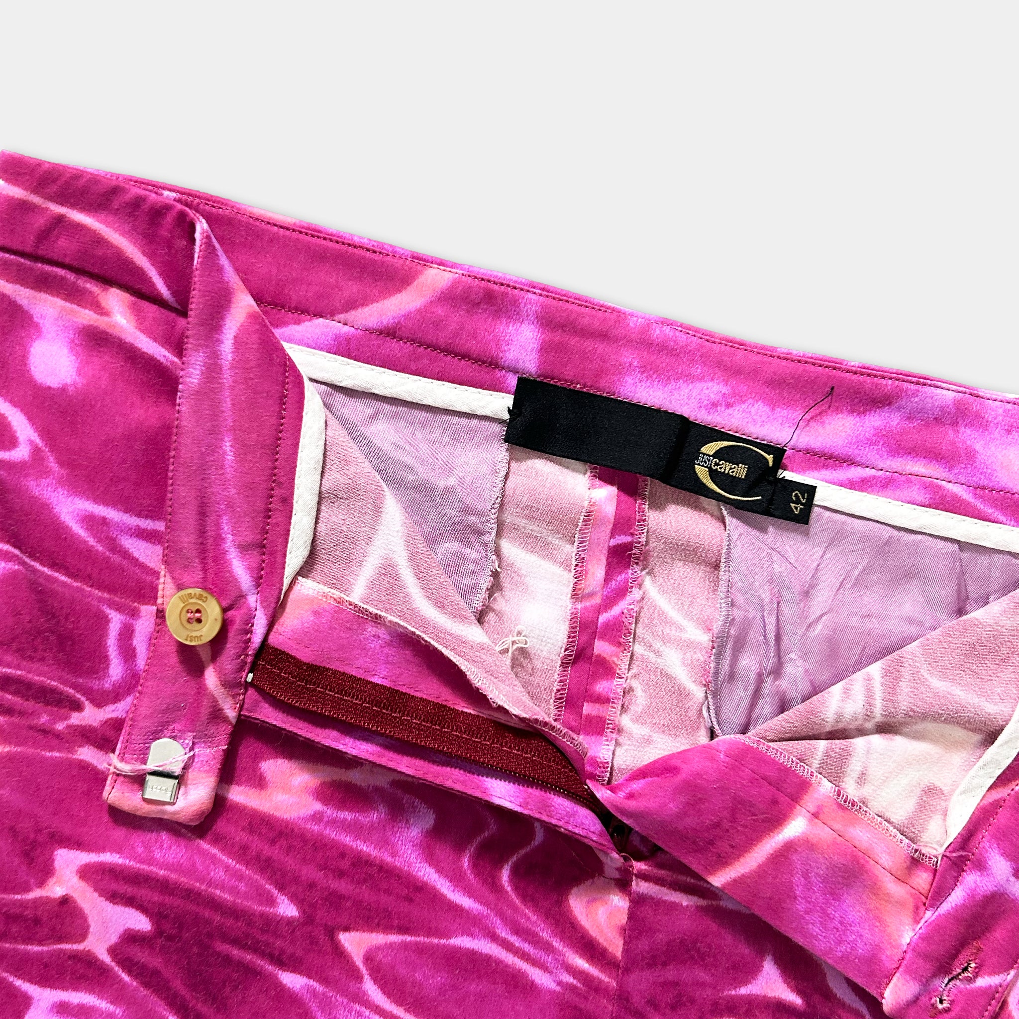 A close-up view of a pair of pink and white patterned pants with a black label attached to the waistband.
