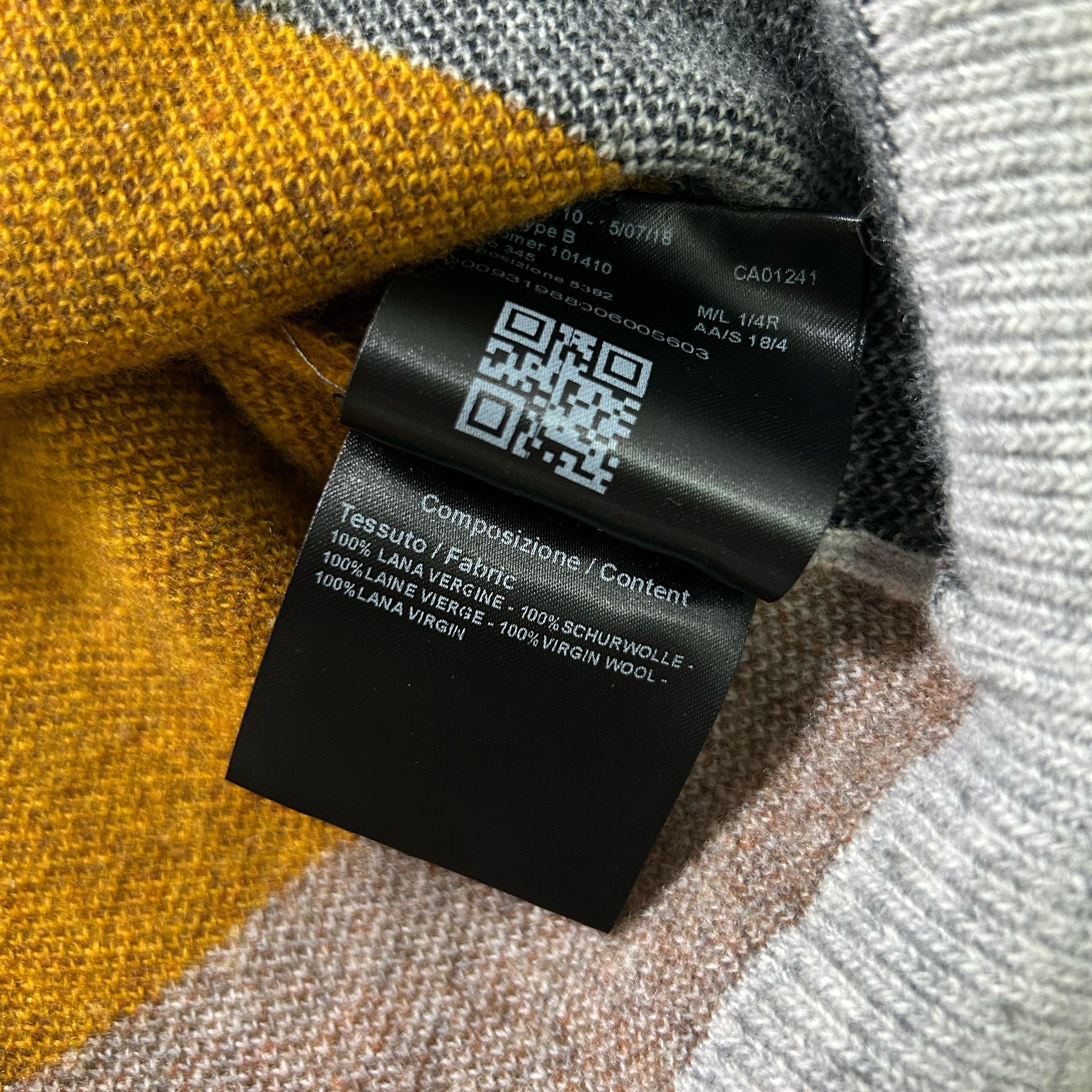 a close-up view of a black label with text and a QR code attached to a fabric, possibly a sweater or a blanket.