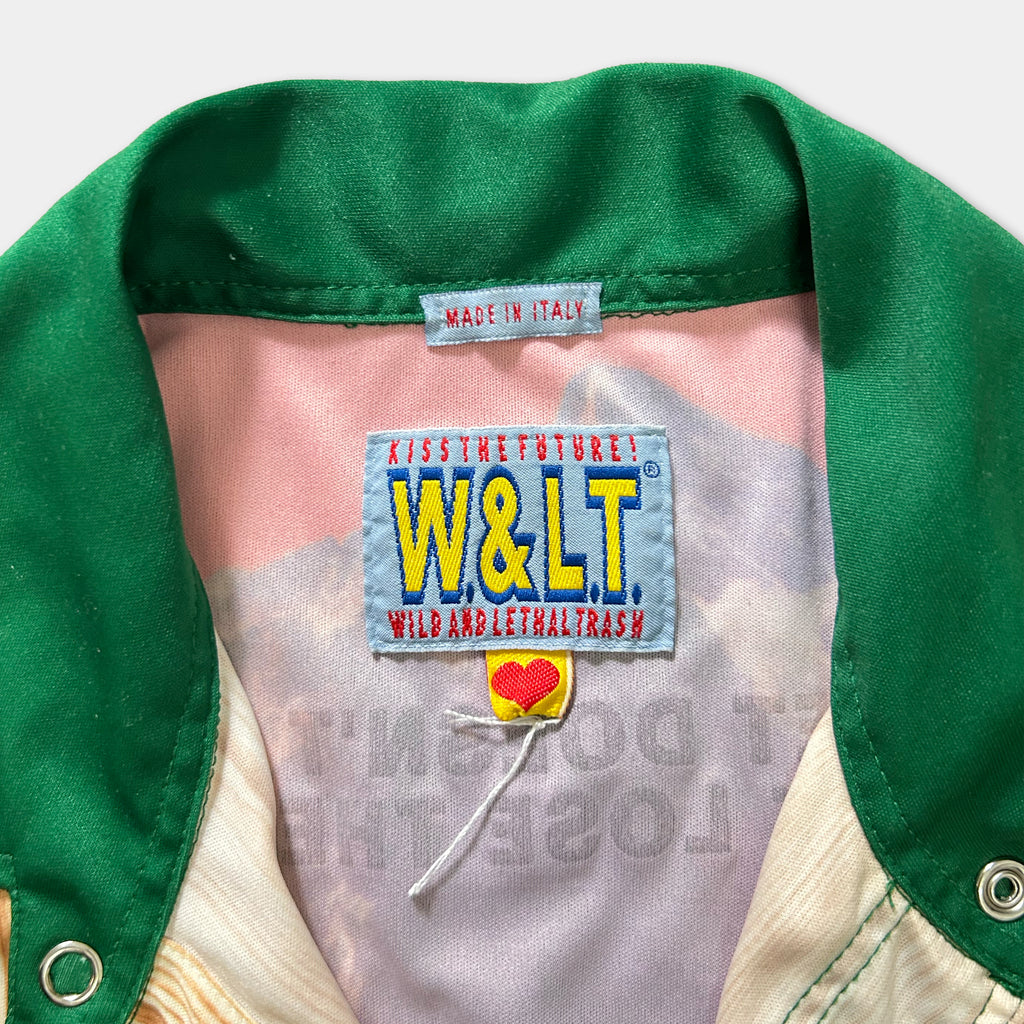 a close-up view of a green and white jacket with a label on the collar, which reads "Made in Italy" and features the W&L logo and the text "Kissing the future! W&L wild and illegal trash".