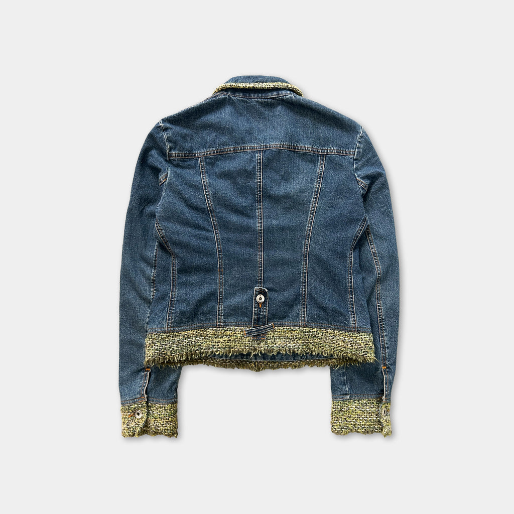 A denim jacket with a fringed trim, featuring a zipper and buttons, is displayed against a plain white background.