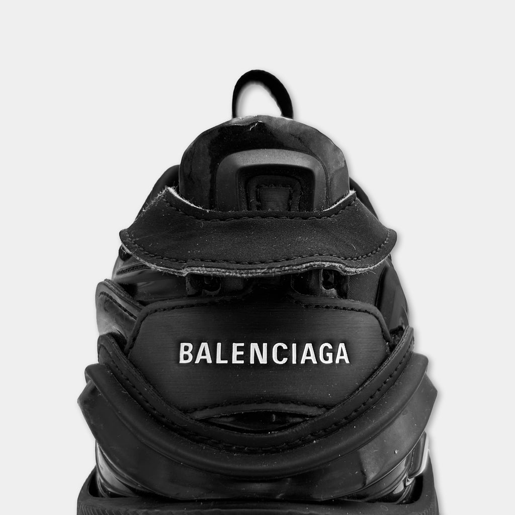A close-up view of a black Balenciaga sneaker, showing the brand name and logo on the back.
