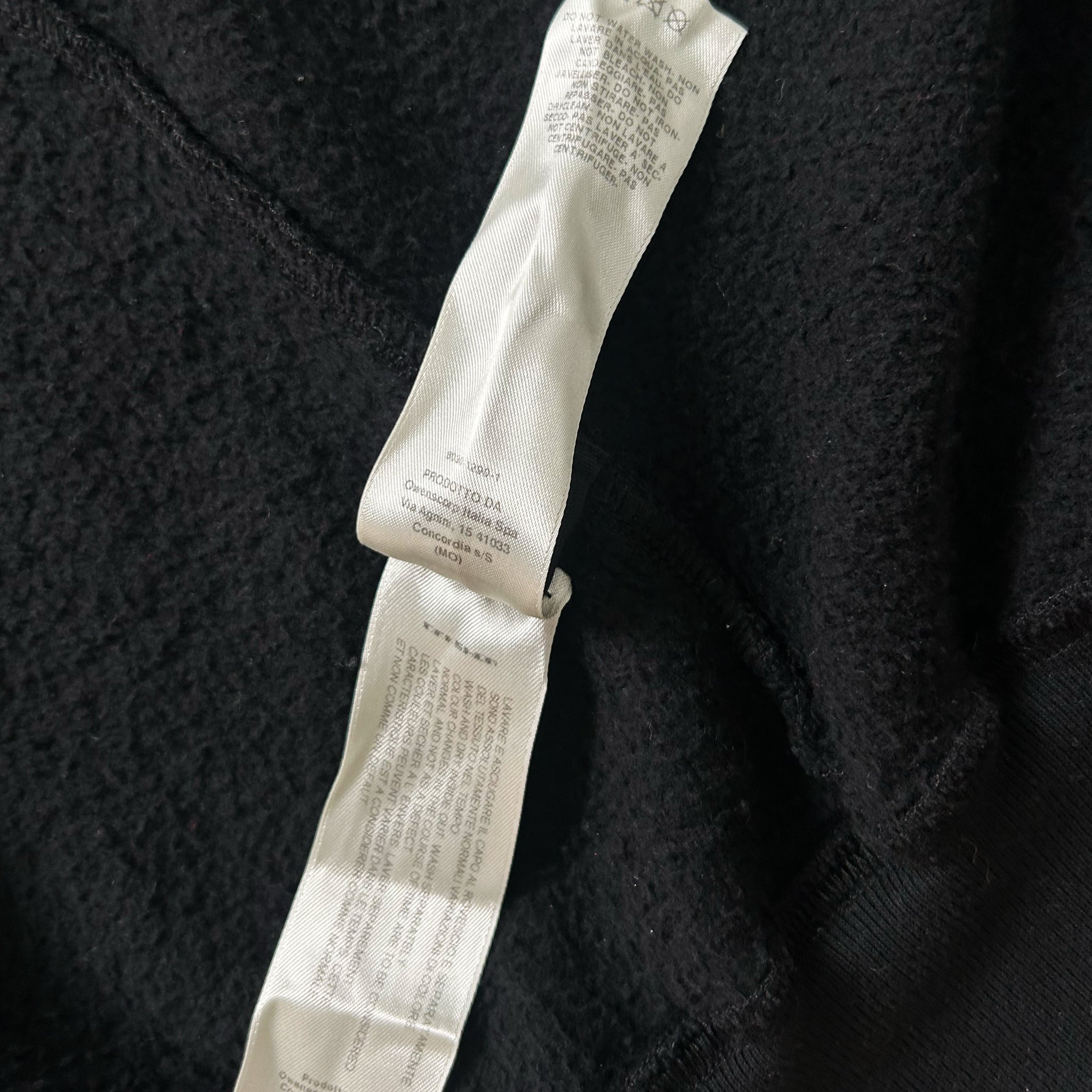 a close-up view of a black fabric with a white label attached to it. The label appears to contain text and instructions related to the fabric, possibly providing information about the product or its care.