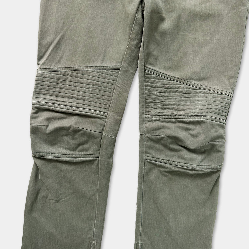A close-up view of a pair of olive green knee-length pants with a distinctive quilted pattern on the knees.