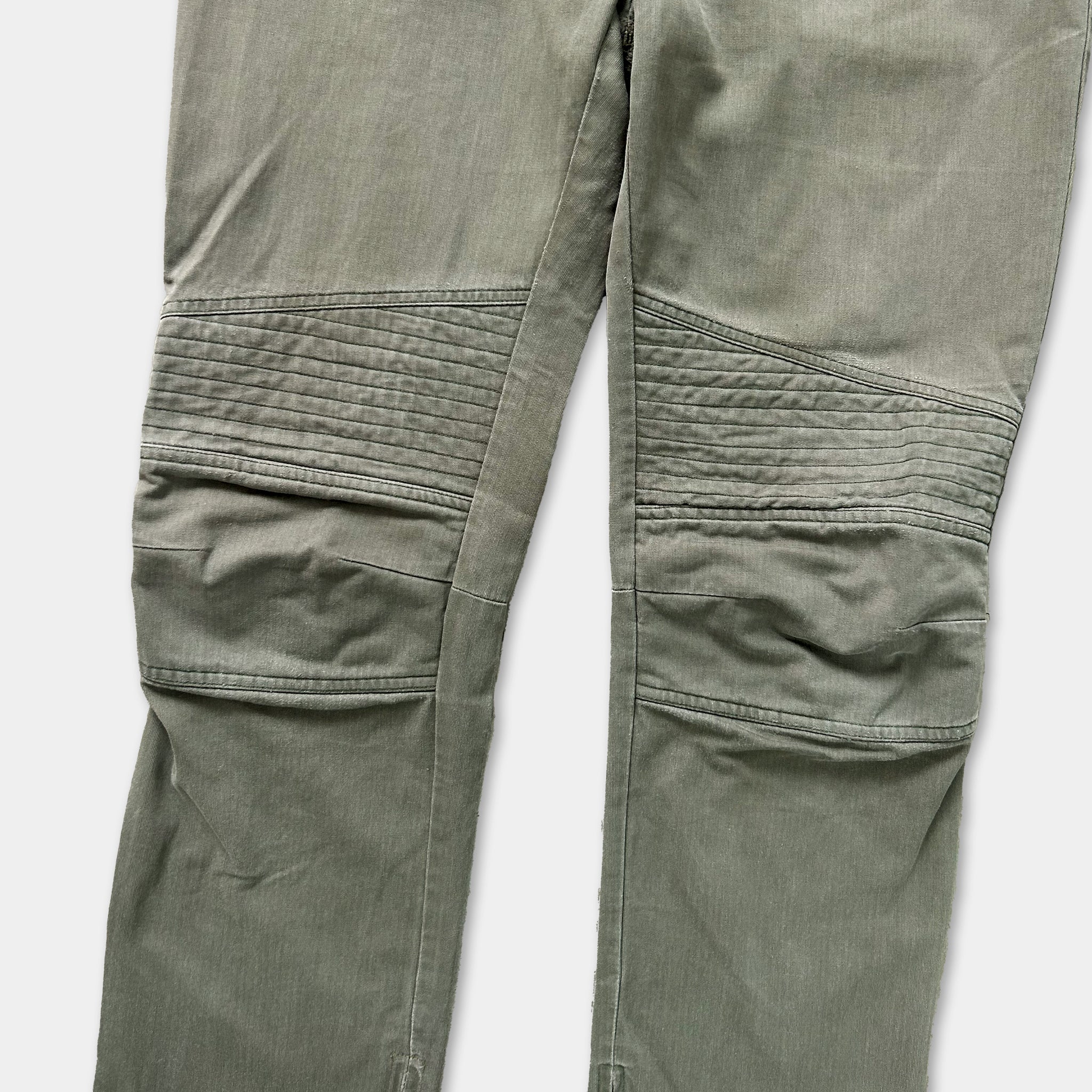 A close-up view of a pair of olive green knee-length pants with a distinctive quilted pattern on the knees.
