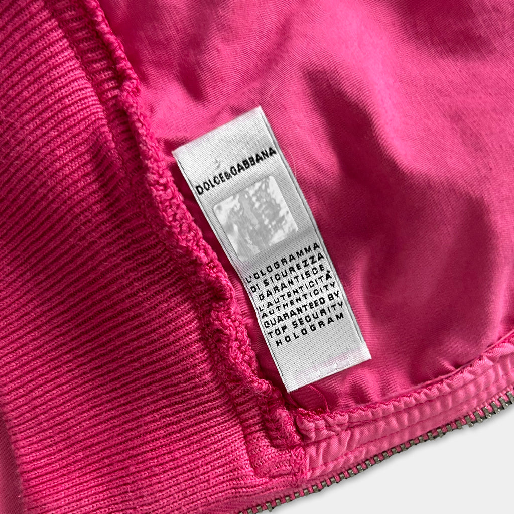A close-up image of a pink fabric with a label attached to it, which appears to be a label from a clothing brand.
