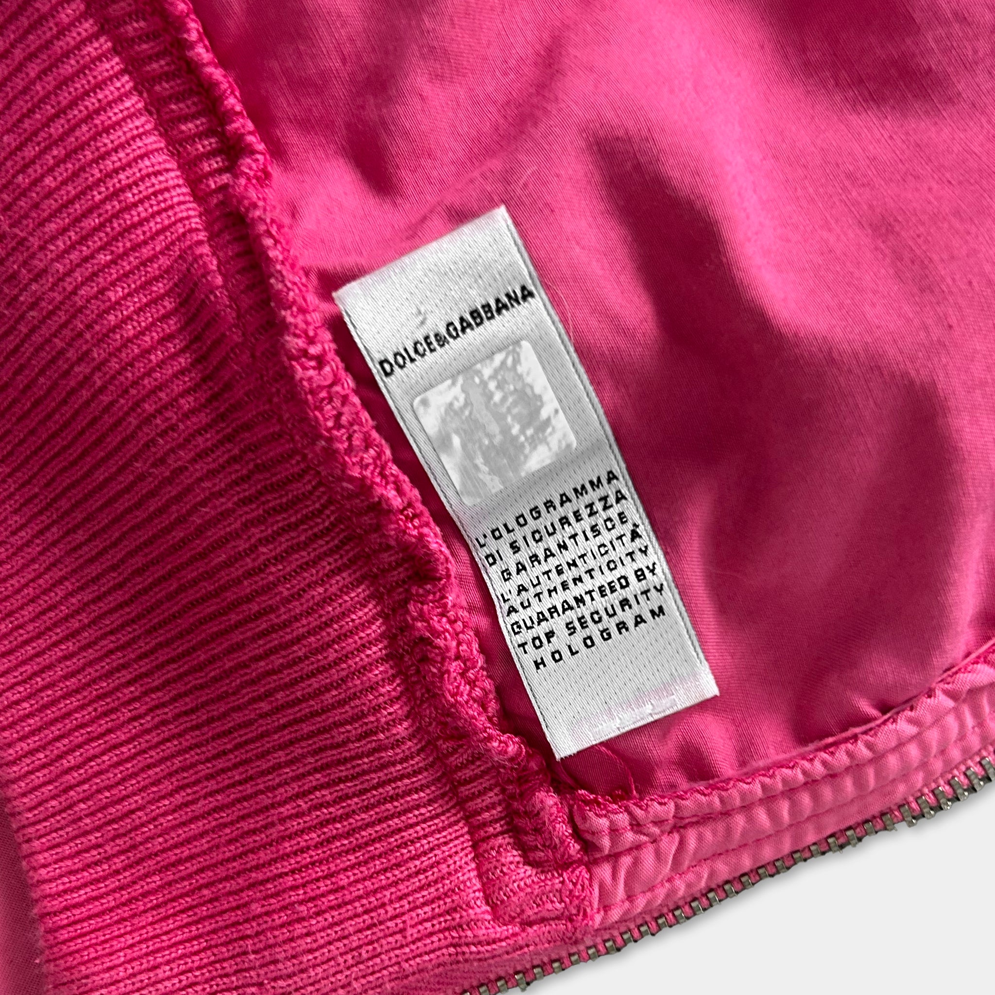 A close-up image of a pink fabric with a label attached to it, which appears to be a label from a clothing brand.