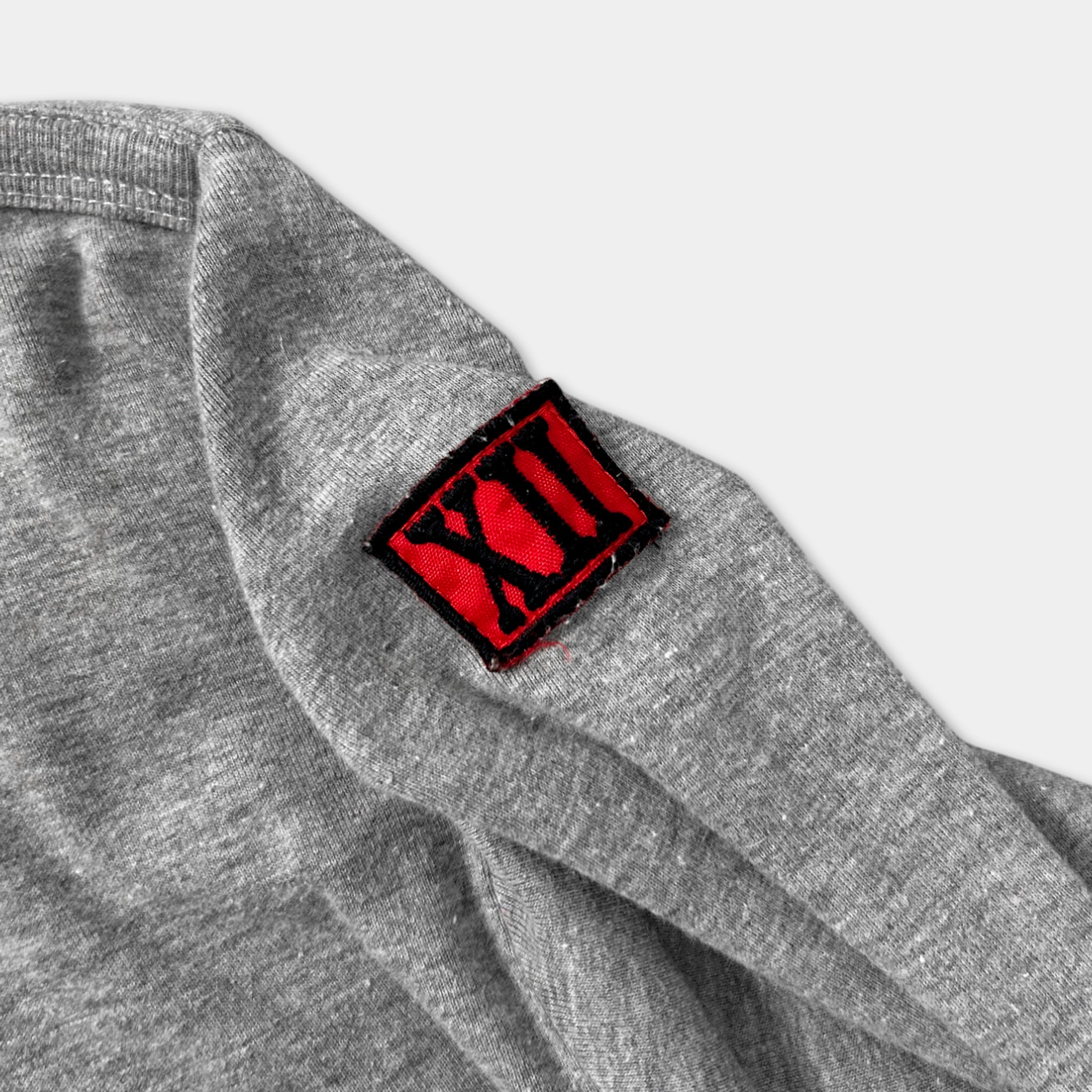 A gray sweatshirt with a red patch on the left side of the sleeve.