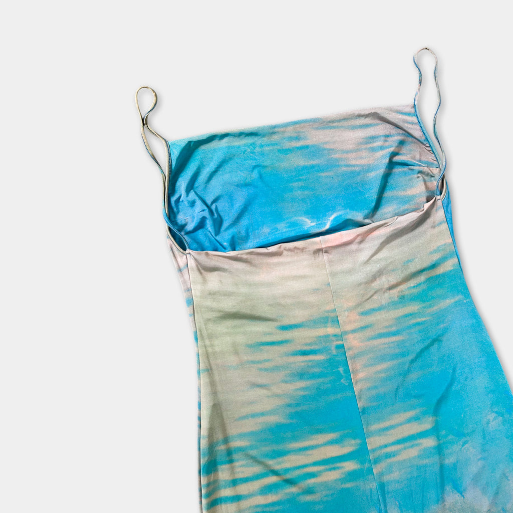 a blue and white patterned dress with a tie-dye design, hanging on a white background.