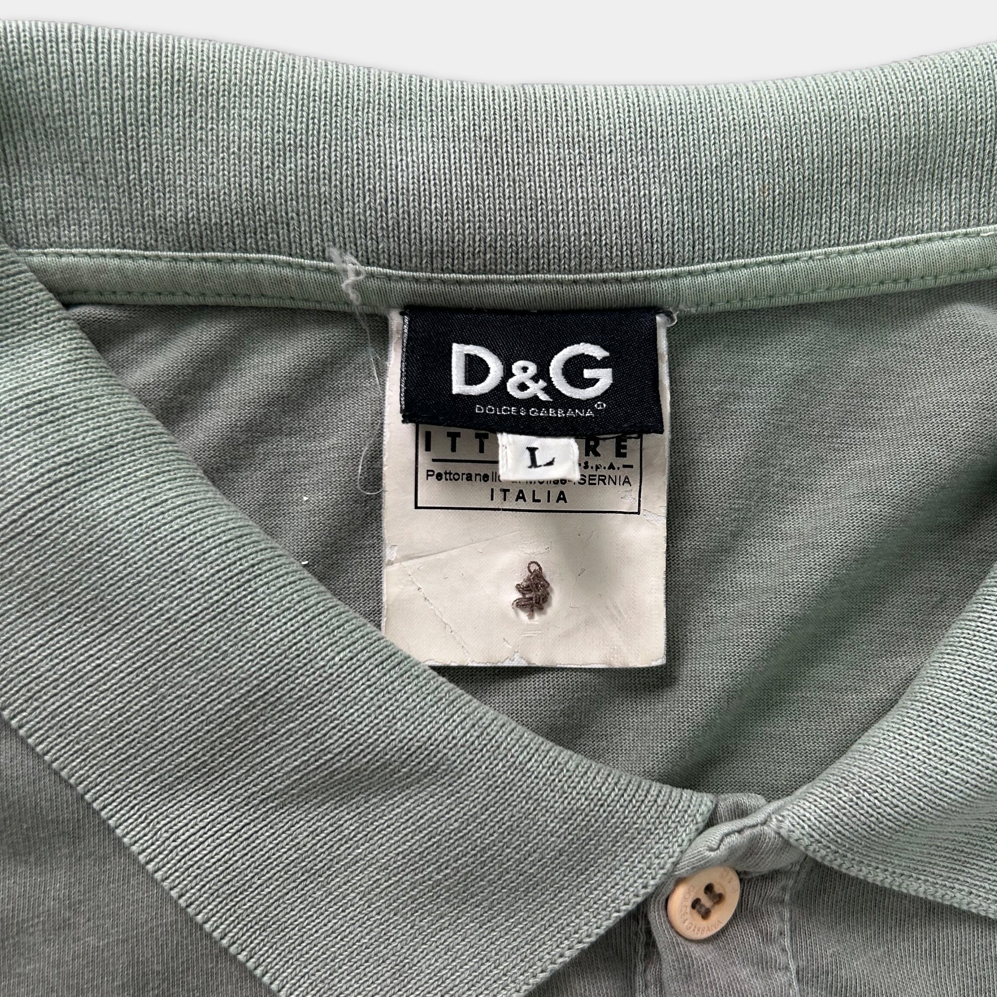 A close-up view of a green polo shirt collar with a D&G logo and a label attached to it.