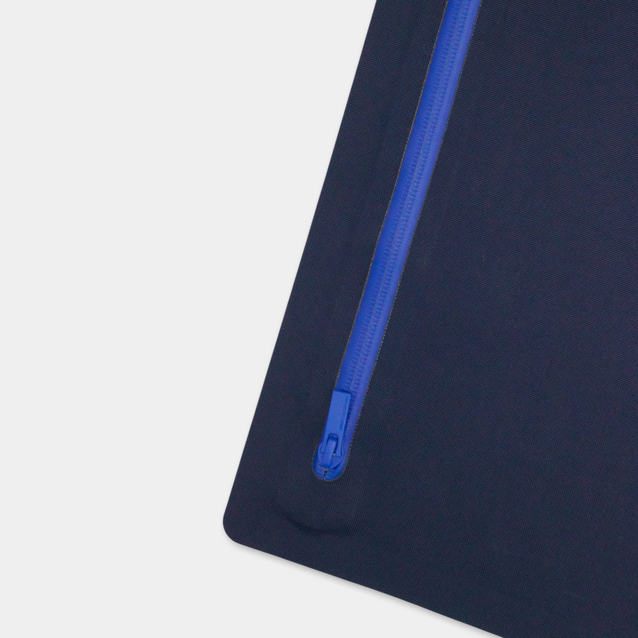 A close-up view of a blue zipper on a dark blue surface.