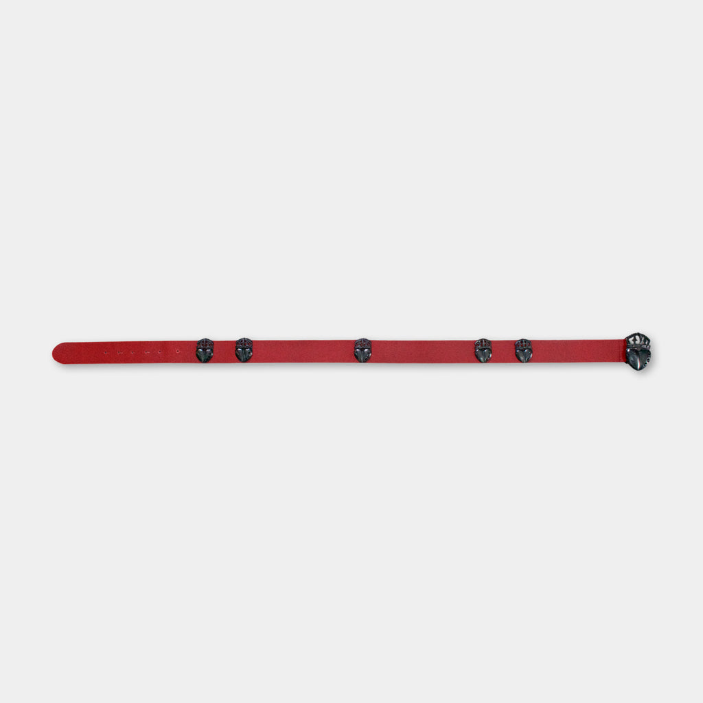 A red belt with black circular embellishments is shown against a plain white background.