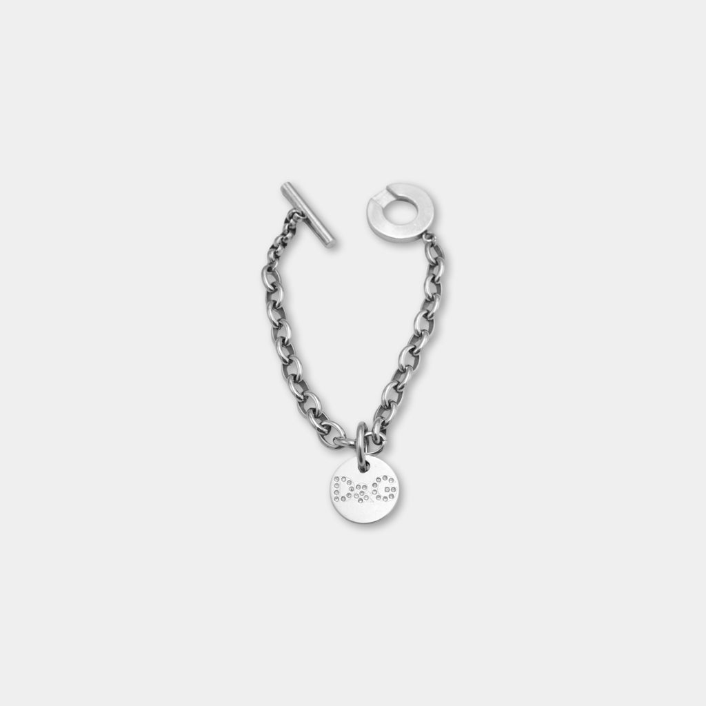 A silver-colored chain bracelet with a small circular charm attached to it.