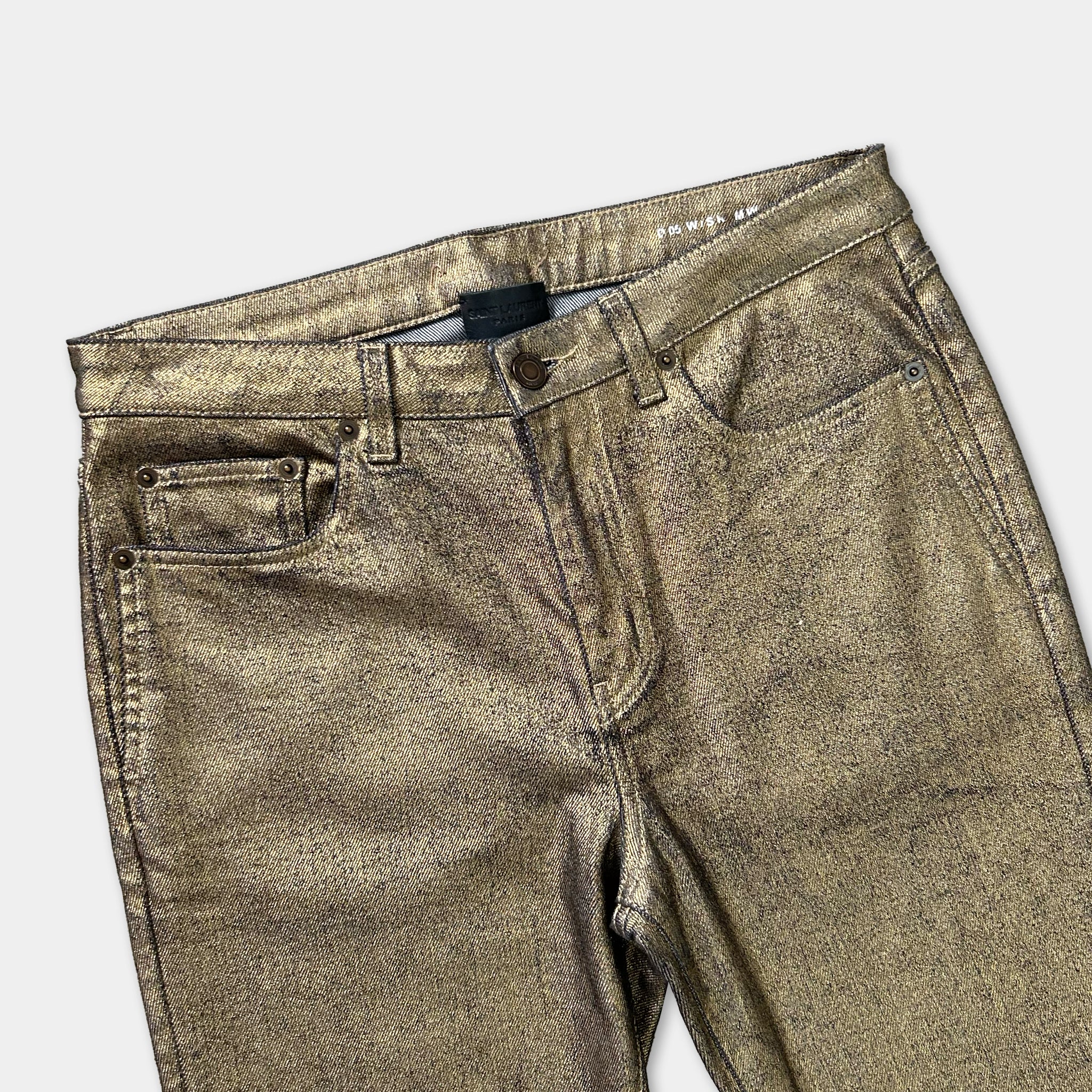 A pair of gold-colored, shiny, and textured jeans with a zipper and pockets.