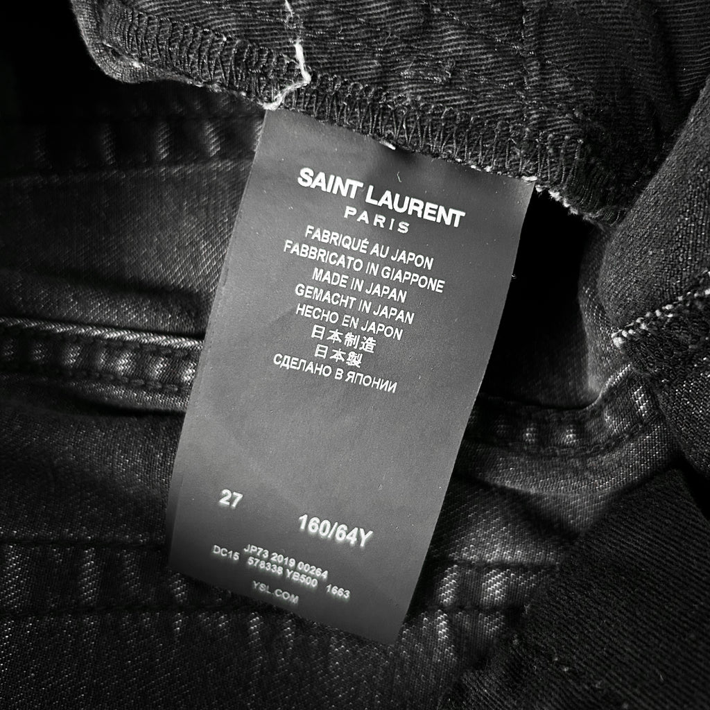 a close-up of a black fabric label with text on it, attached to a piece of clothing.