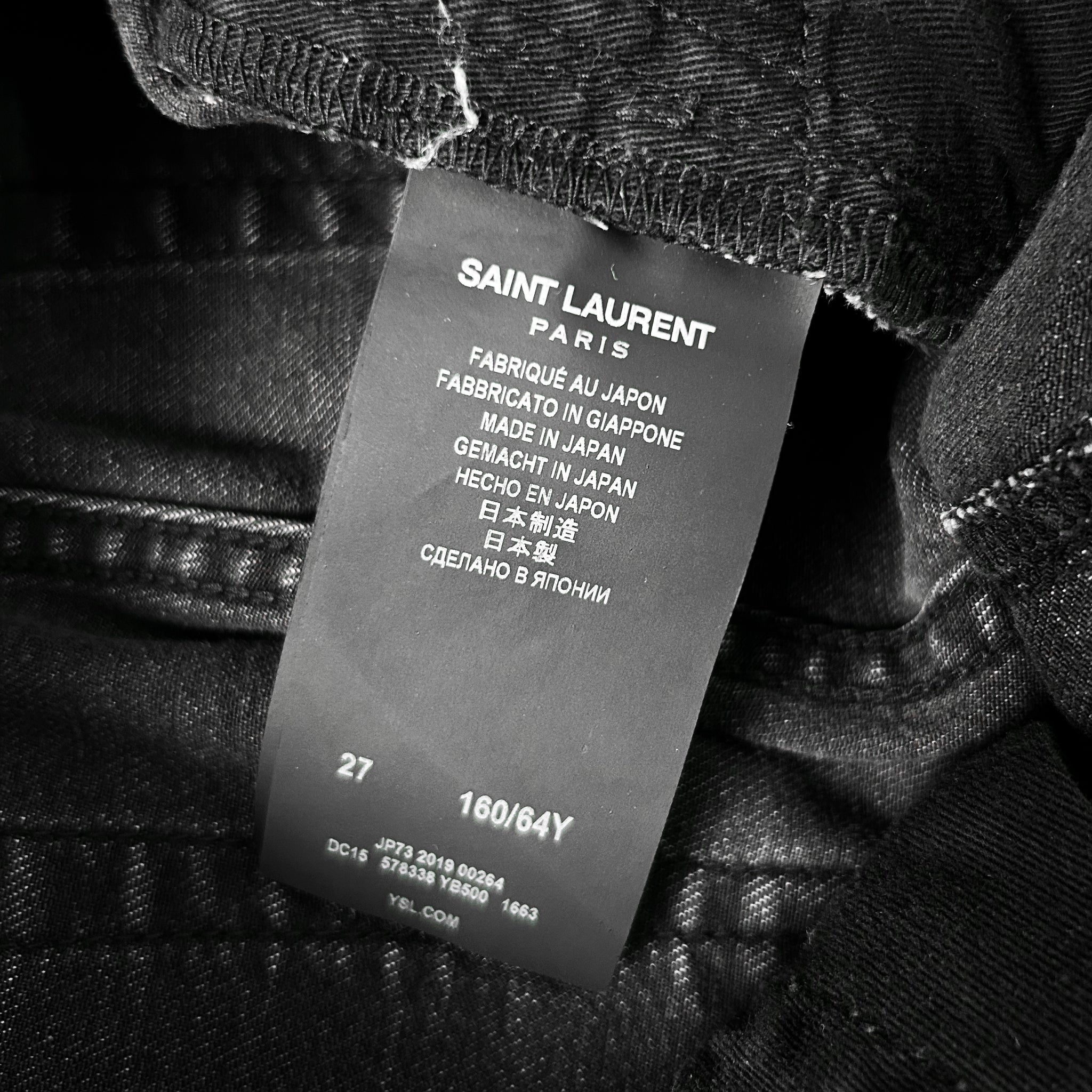 a close-up of a black fabric label with text on it, attached to a piece of clothing.