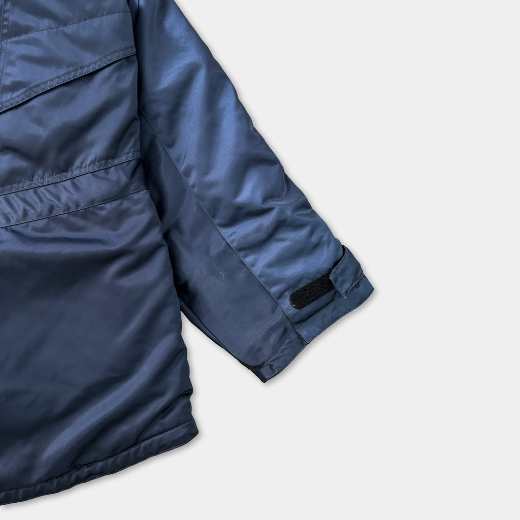 A close-up view of a navy blue jacket with a black patch on the sleeve.