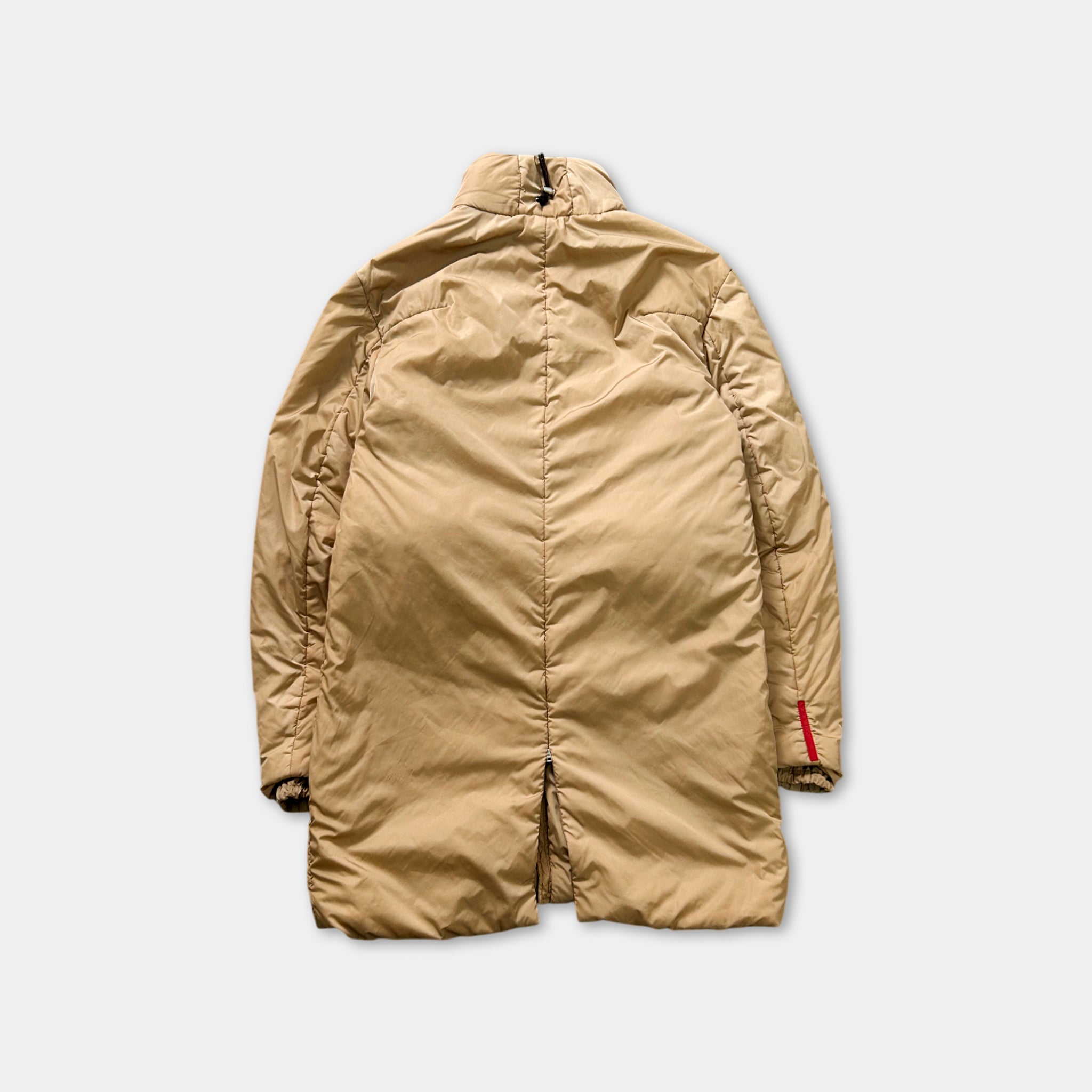 A tan-colored coat with a red zipper detail is shown against a plain white background.