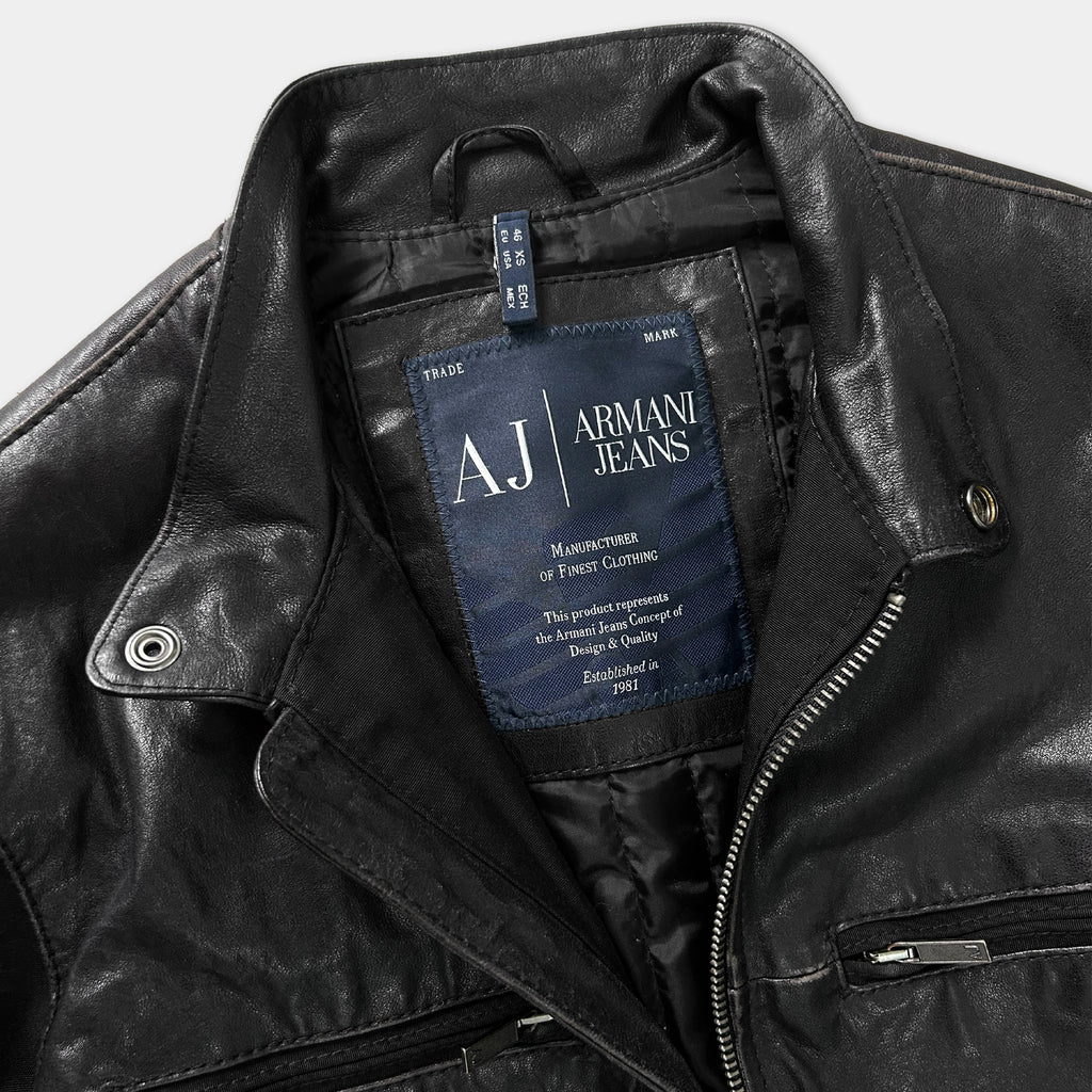 A close-up view of a black leather jacket with a label on the collar.