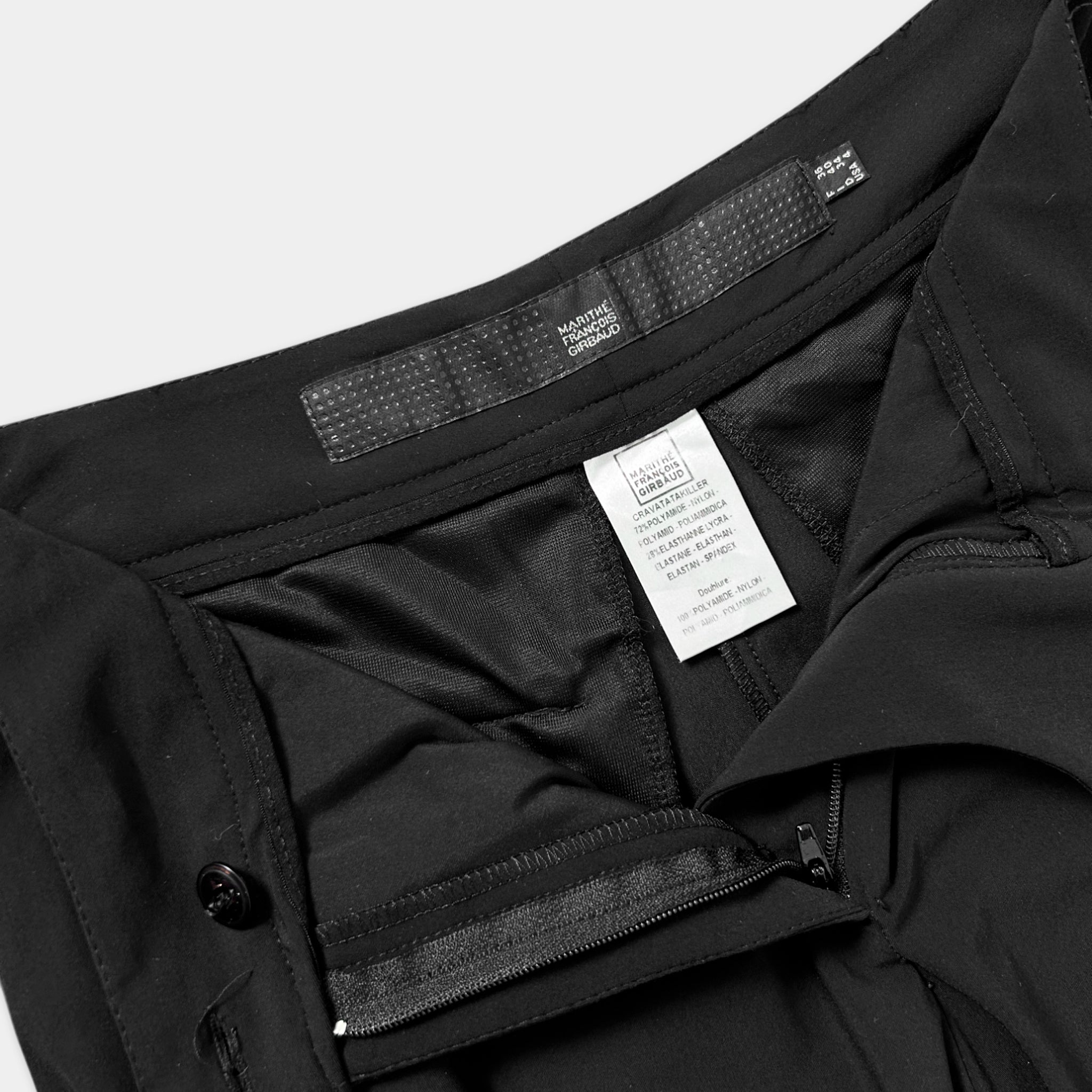 a close-up view of a black pair of pants, with a label attached to the waistband.