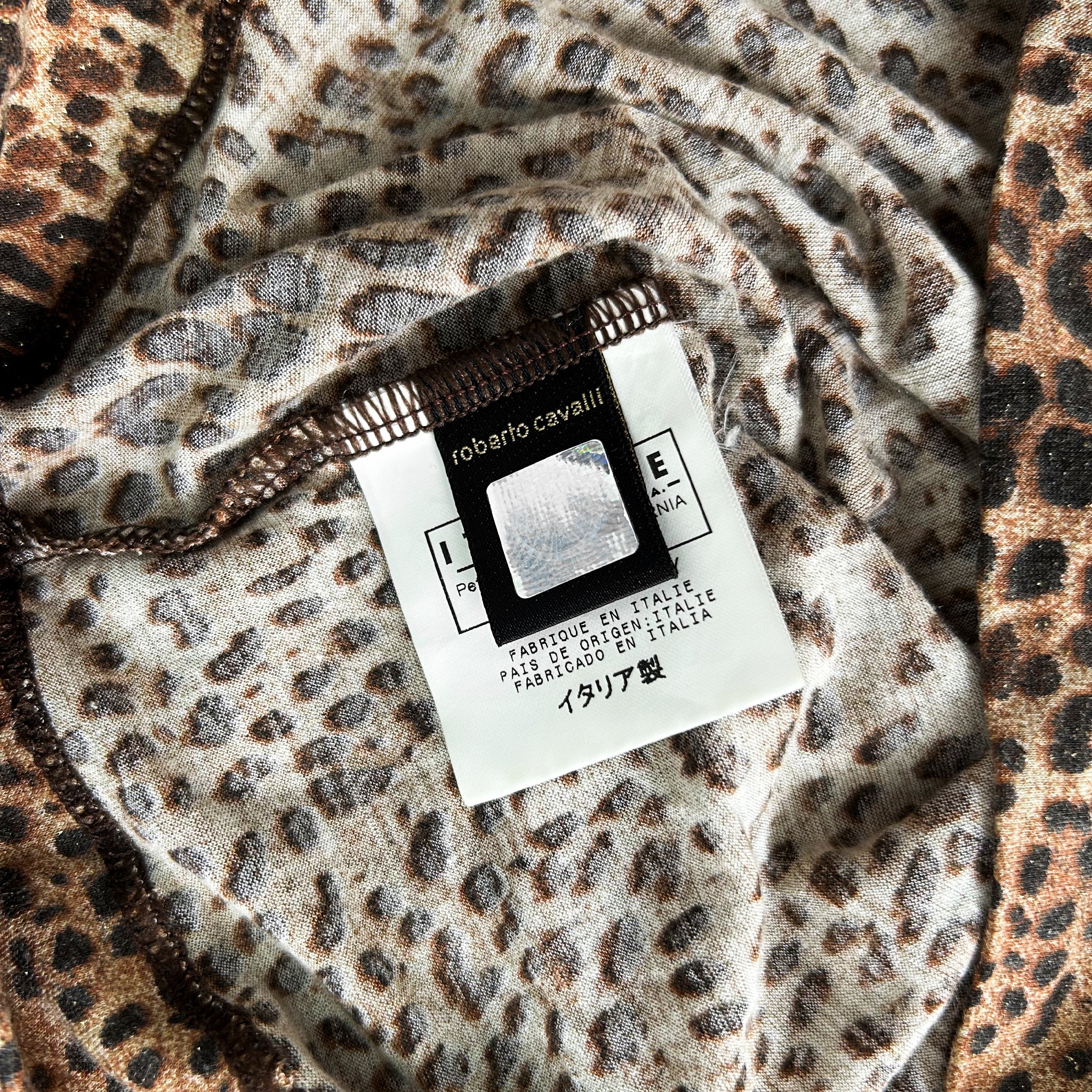 a close-up view of a fabric with a leopard print pattern, and there is a label attached to it.