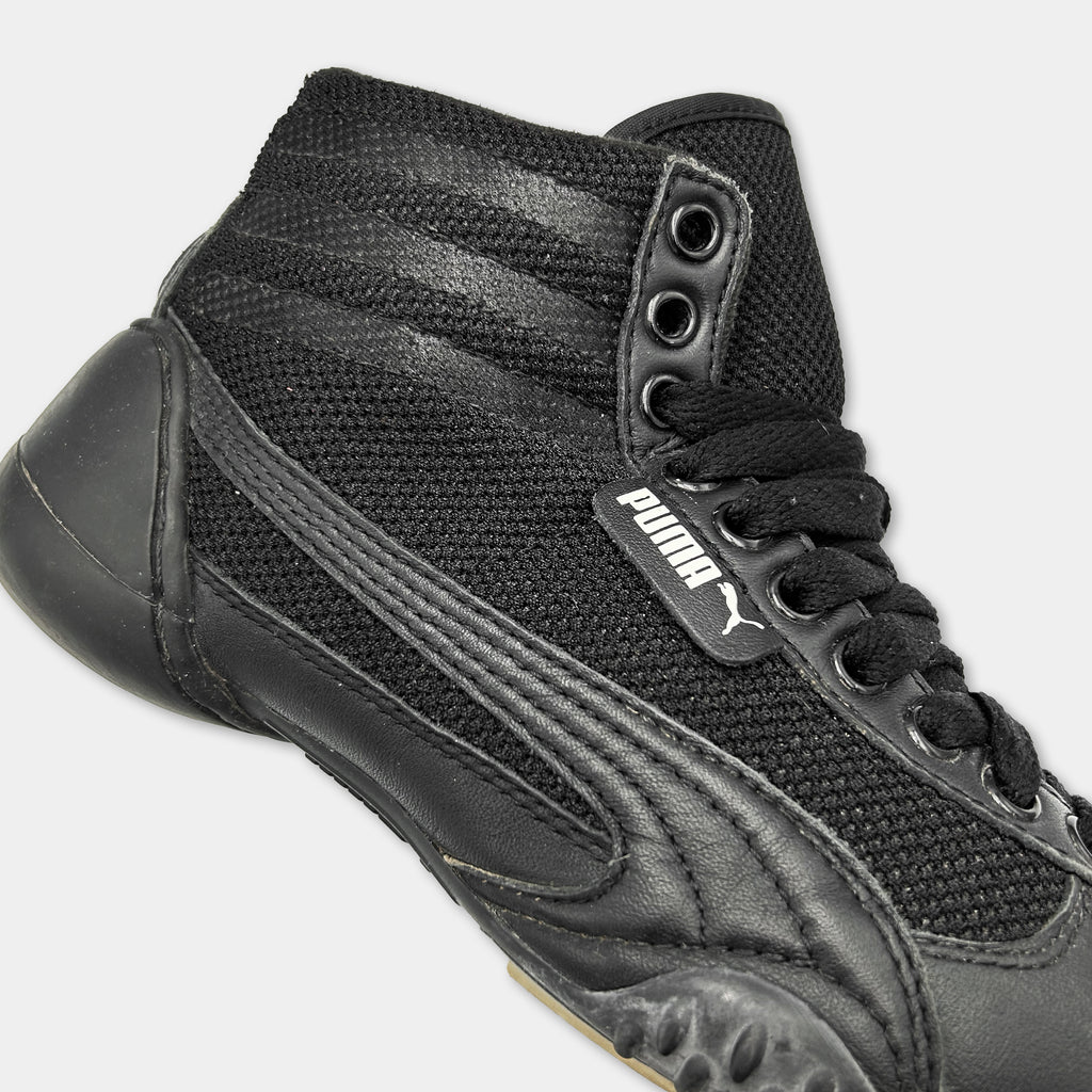 A close-up view of a black and white high-top sneaker with a mesh upper and a black lace-up design.