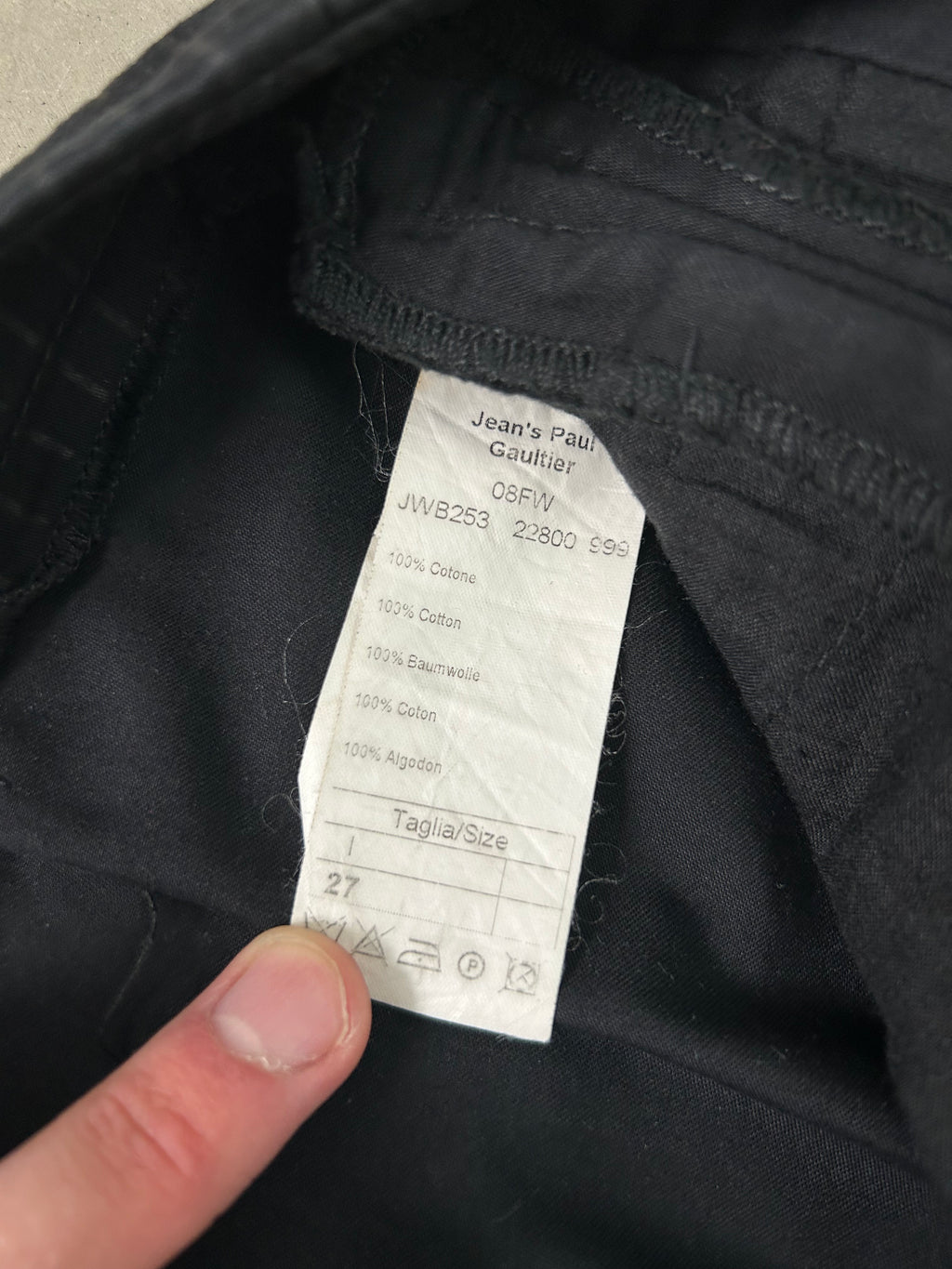 A close-up view of a black fabric, possibly a piece of clothing, with a label attached to it. The label appears to contain text and symbols, but the image does not contain any text that is less than 500 characters.