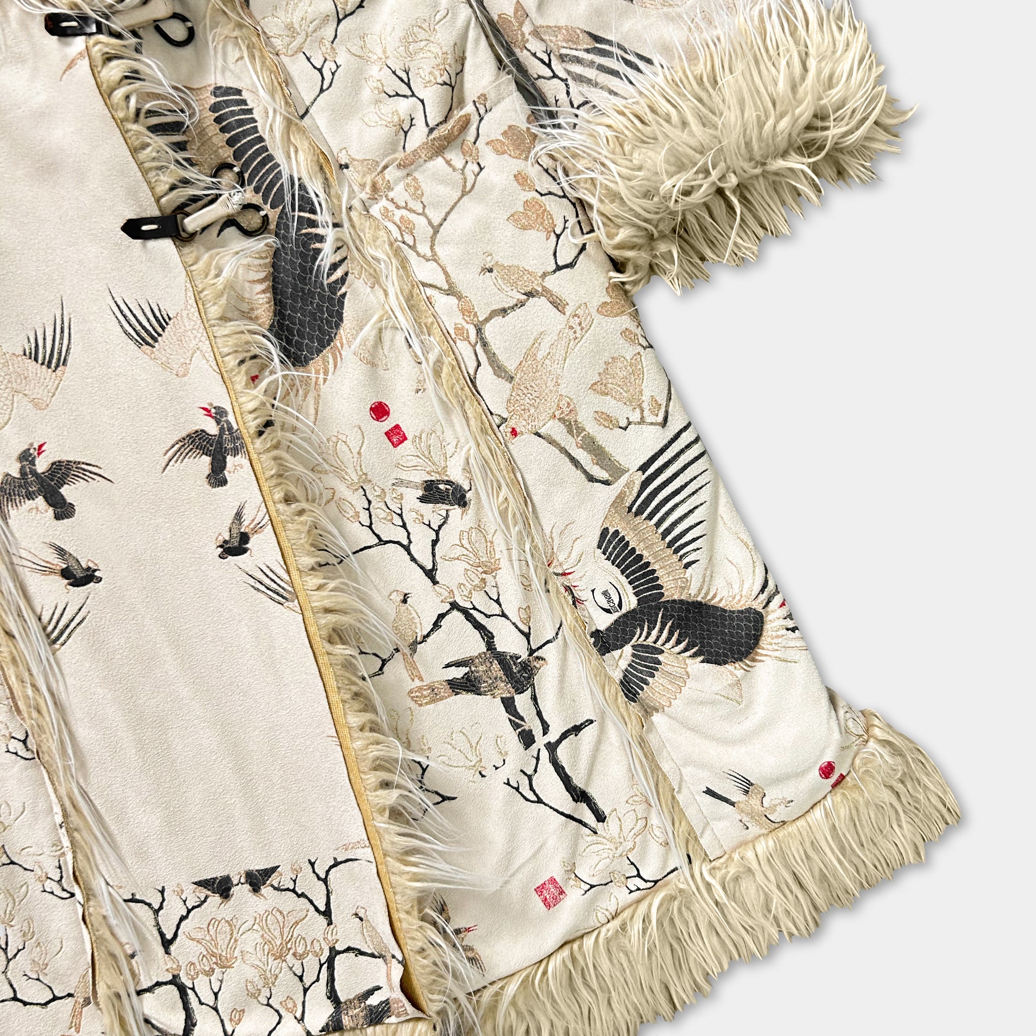 a close-up view of a decorative fabric with a floral pattern and a fringe trim.