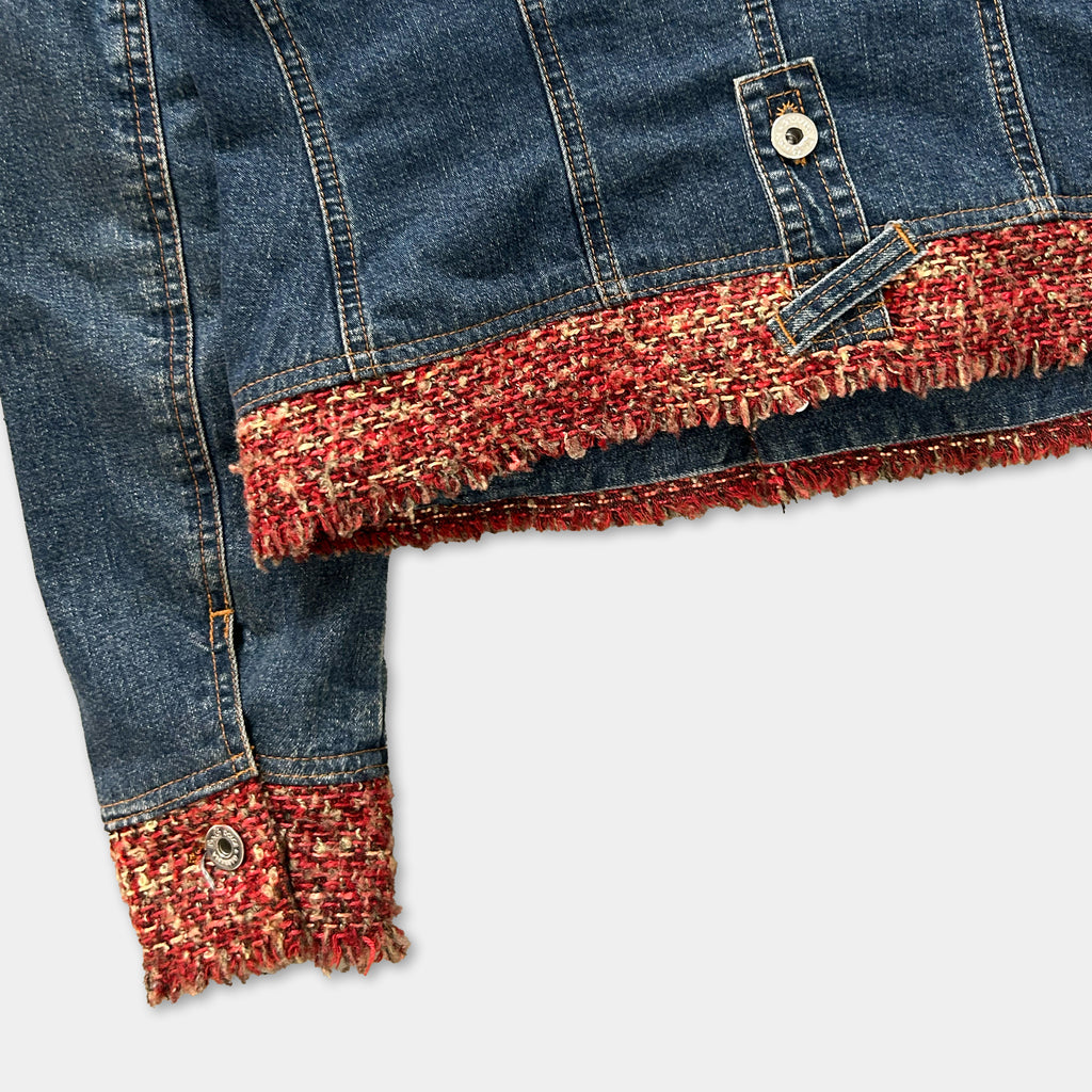 A close-up view of a denim jacket with a red and gold fringe trim.