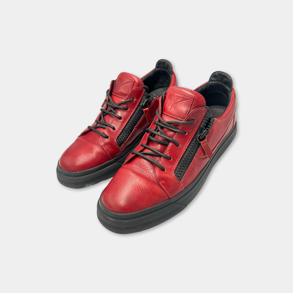 A pair of red leather sneakers with black zippers and soles.