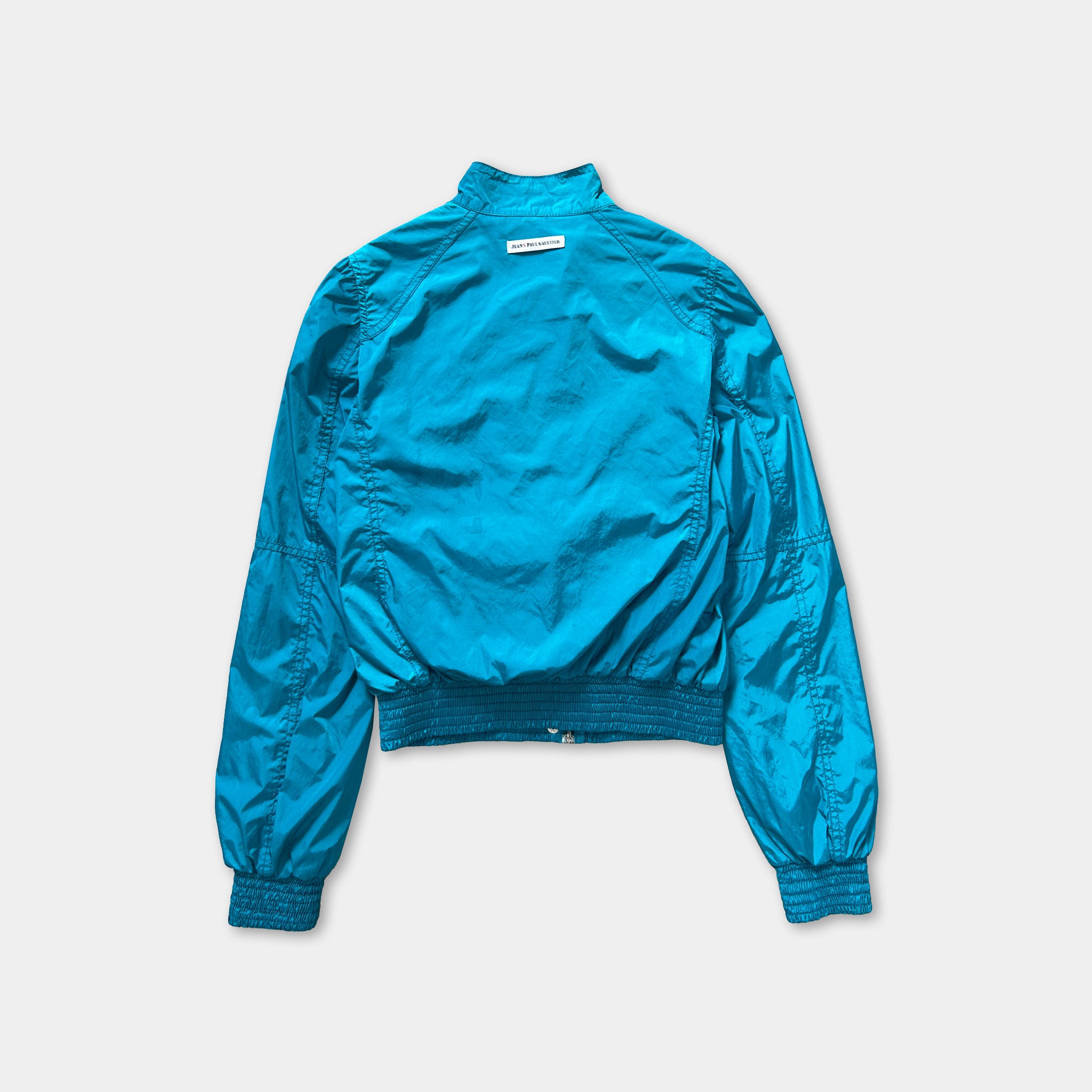 A turquoise-colored jacket with a high collar and long sleeves is shown against a white background.