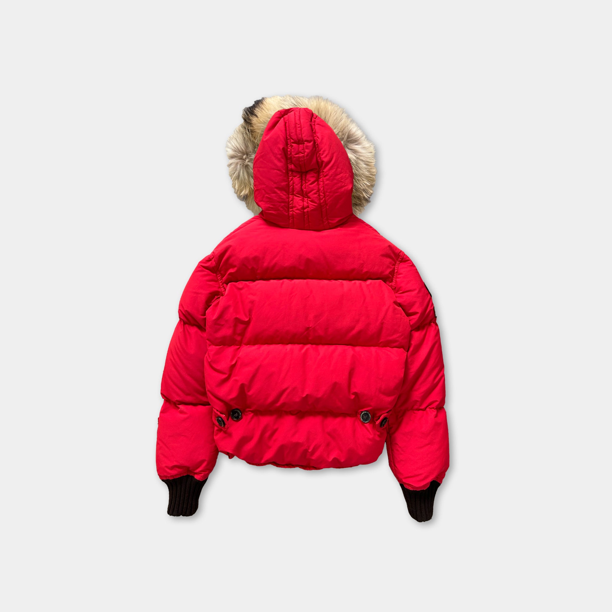 A bright red puffy jacket with a fur-lined hood is shown against a white background.