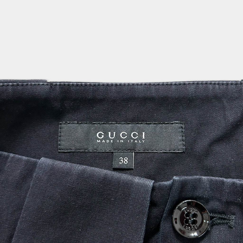 a close-up view of a Gucci clothing label, specifically a pair of dark blue pants. The label displays the Gucci brand name and the text "MADE IN ITALY".