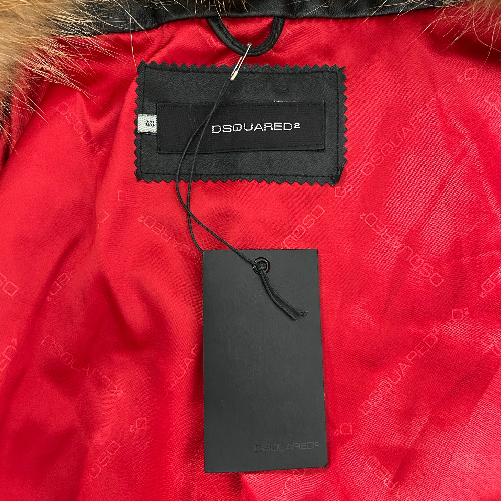 a close-up view of a red fabric with a black tag attached to it, displaying the brand name "DSQUARED".