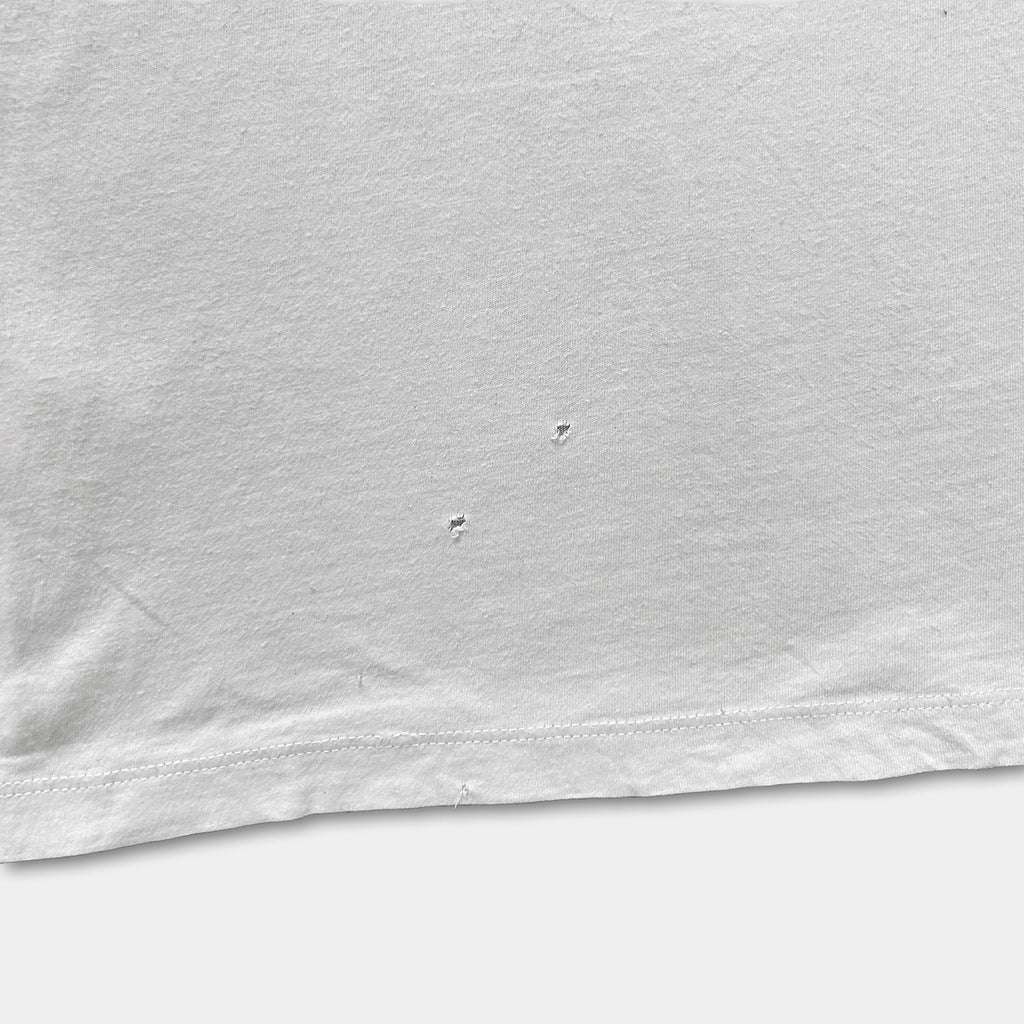 The image is a close-up of a white fabric with two small holes or tears in the fabric.