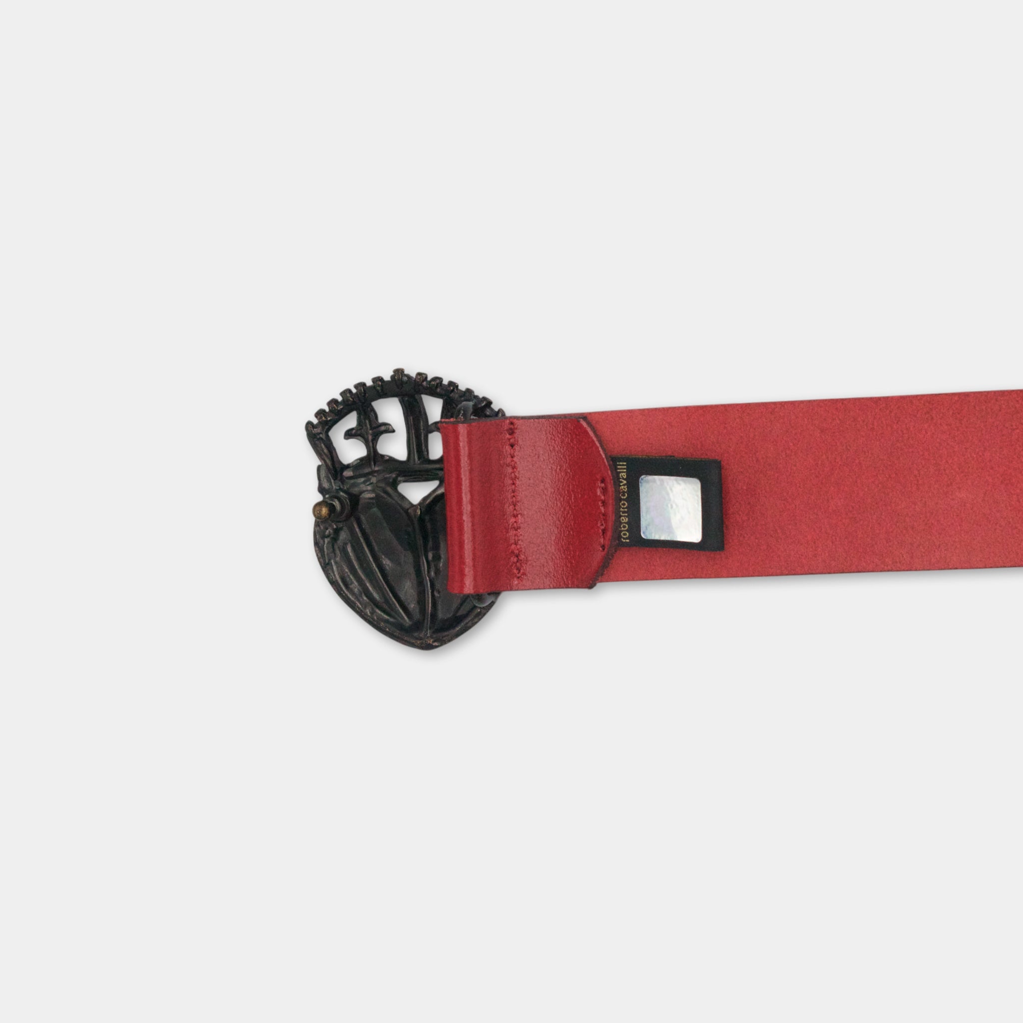 A red leather belt with a black metal buckle featuring a decorative design.