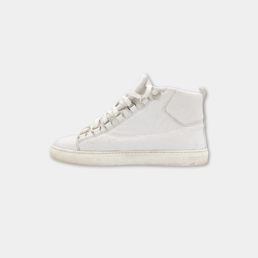 A single white sneaker with a high top and low sole, shown against a plain white background.