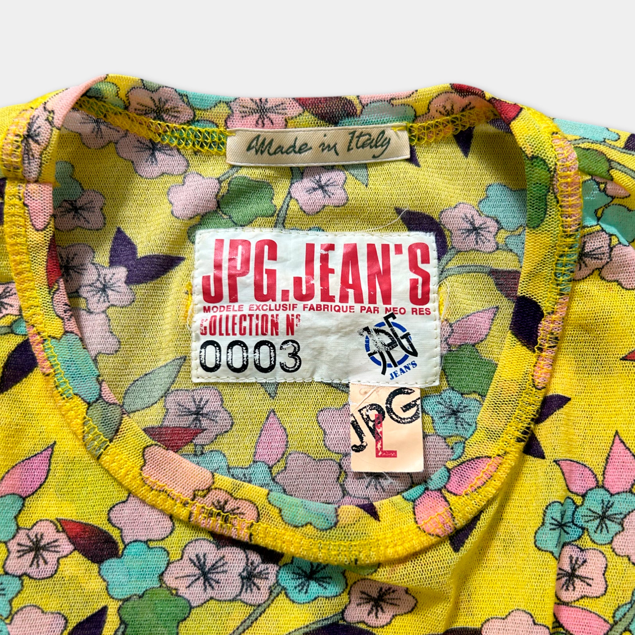 a yellow floral print shirt with a label on the collar, indicating that it is a handmade item from Italy.