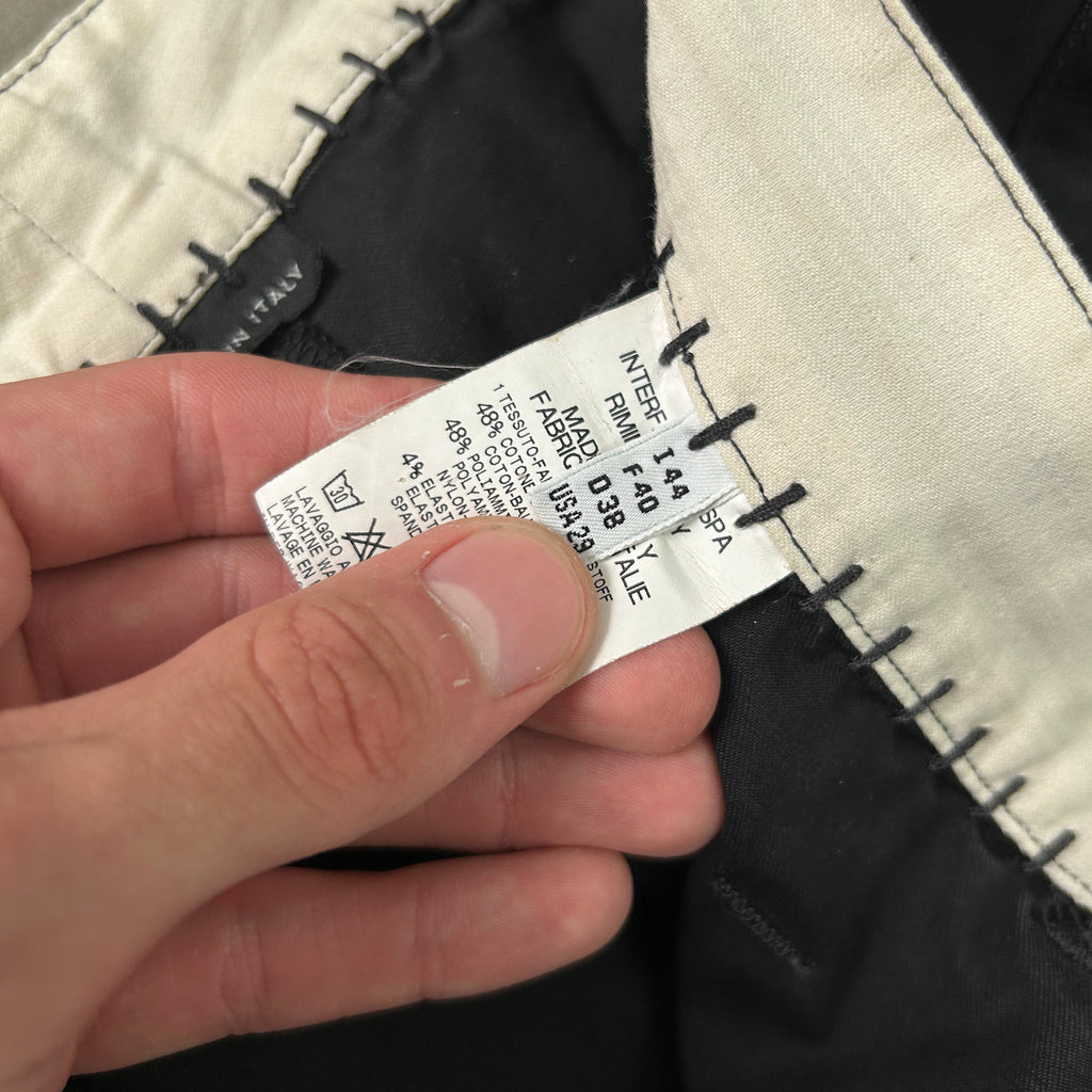 A person's hand holding a label with text and numbers, possibly from a garment or product.