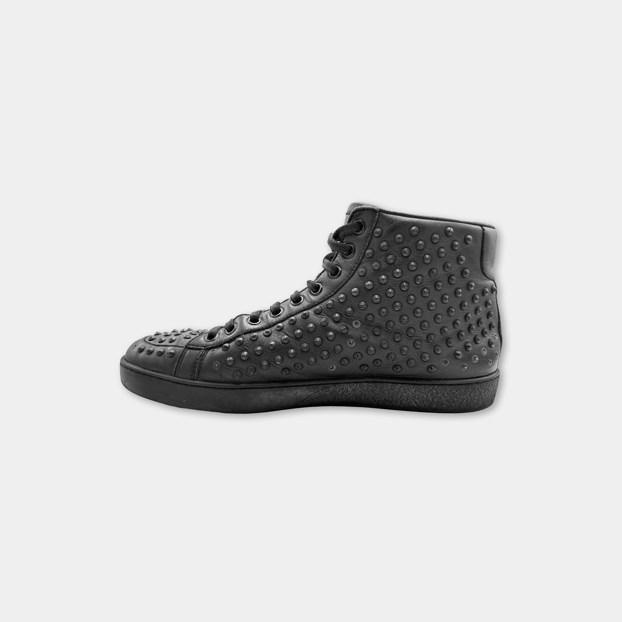A black high-top sneaker with a textured surface and studded pattern.
