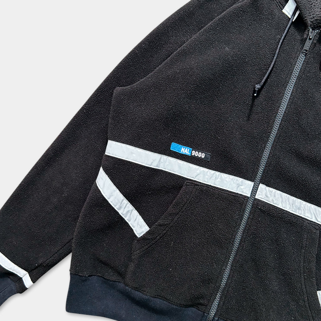 A black zip-up jacket with a white stripe on the sleeves and a blue label on the chest.
