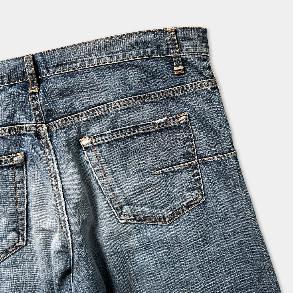 A close-up view of a pair of blue jeans with a pocket and zipper detail.