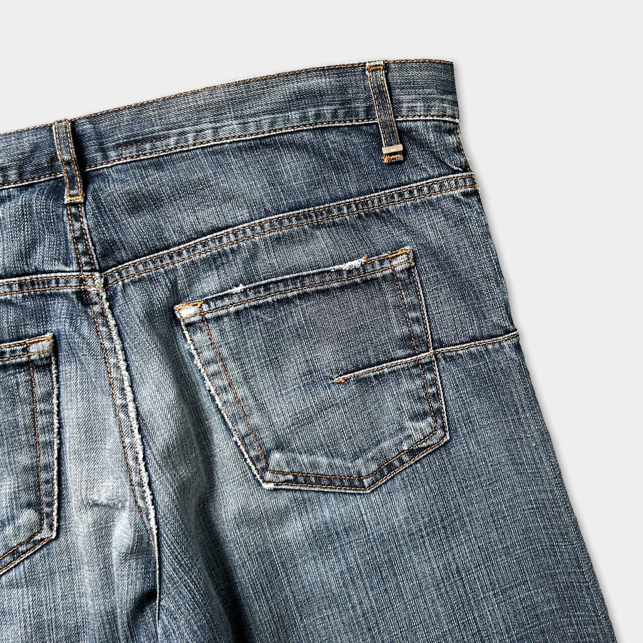 A close-up view of a pair of blue jeans with a pocket and zipper detail.