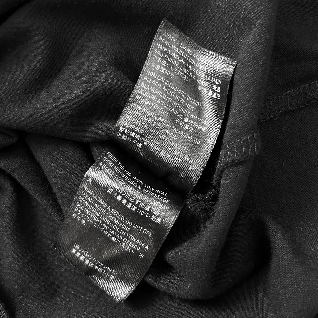 a close-up view of a black fabric, possibly a garment or textile, with a label attached to it. The label contains text in a foreign language, which appears to be instructions or information related to the product.