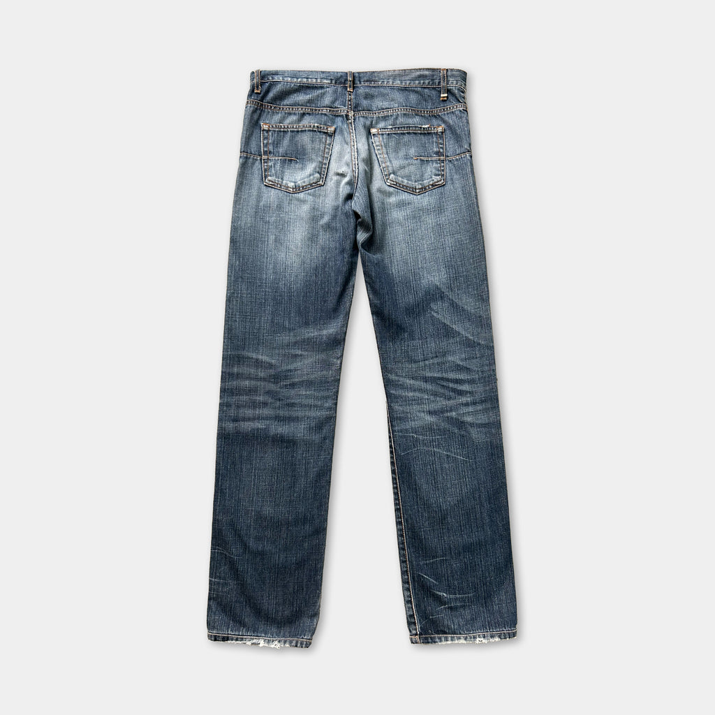 A pair of blue jeans with visible signs of wear and tear, including faded colors and creases.