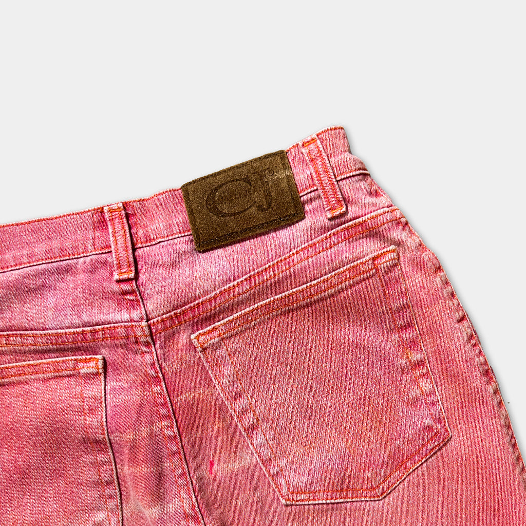 A pair of red denim jeans with a brown leather patch on the back pocket.