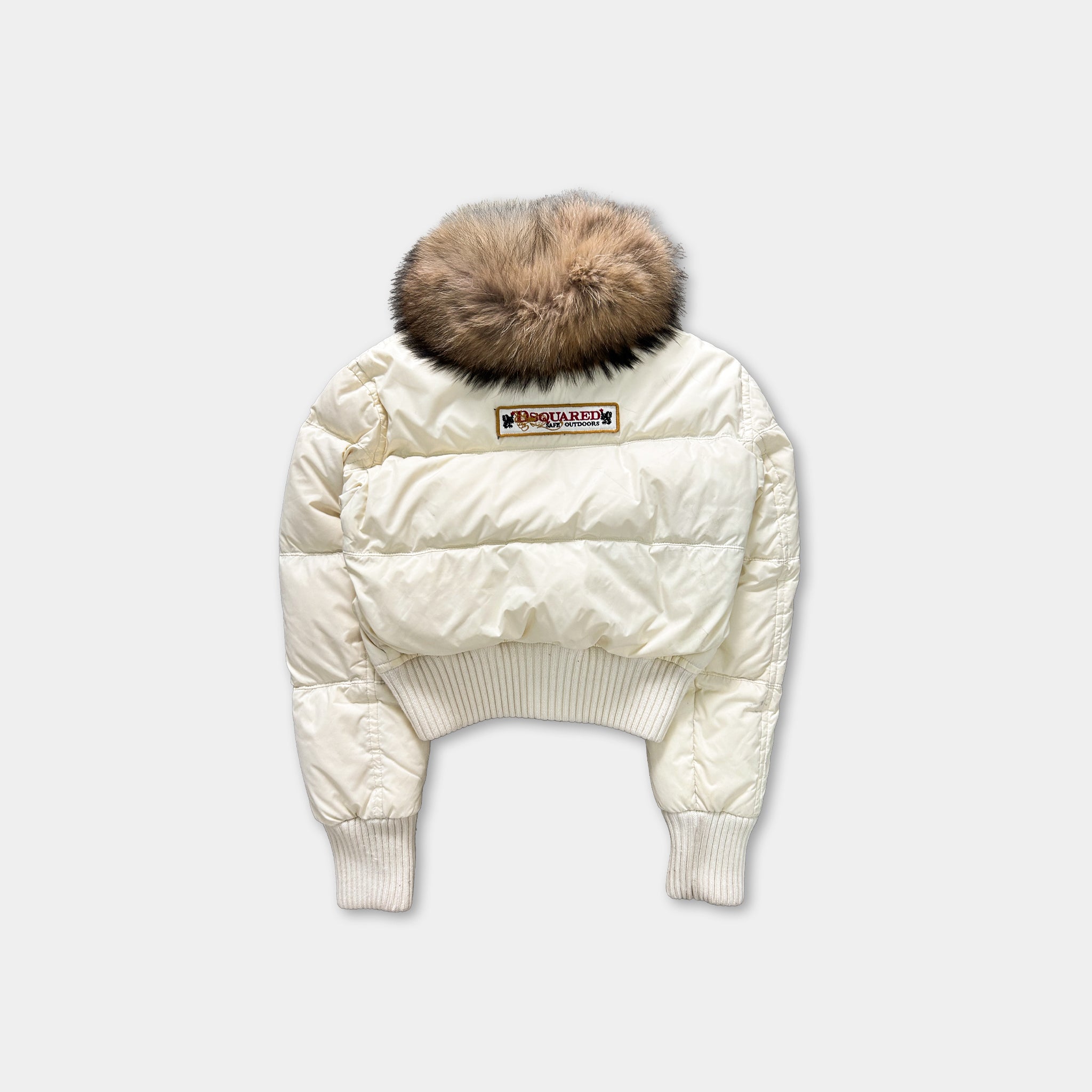 A white puffy jacket with a fur collar and a patch on the back.