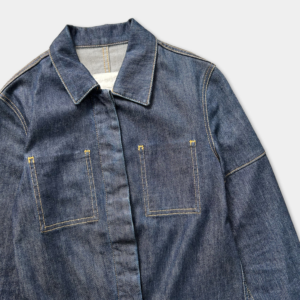 A close-up view of a blue denim jacket with a collar, buttons, and pockets.