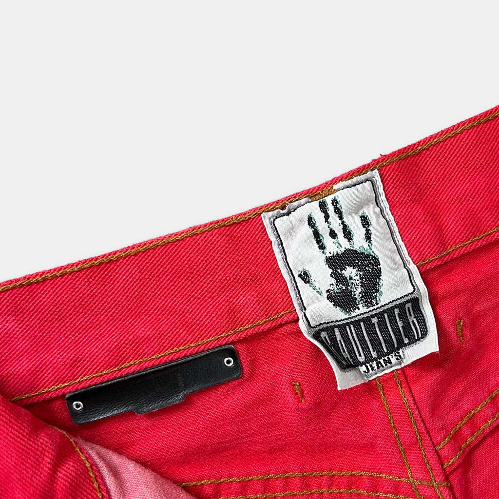 A red pair of jeans with a label attached to the waistband.