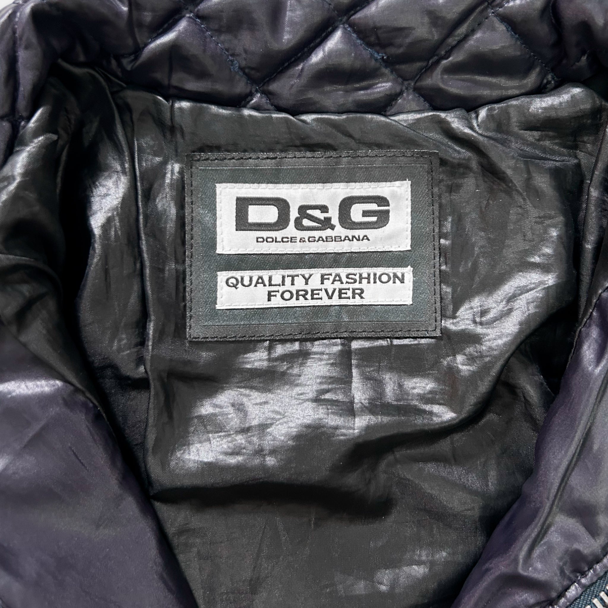 a close-up view of a black jacket with a label on the back, displaying the brand name and slogan "Quality Fashion Forever".