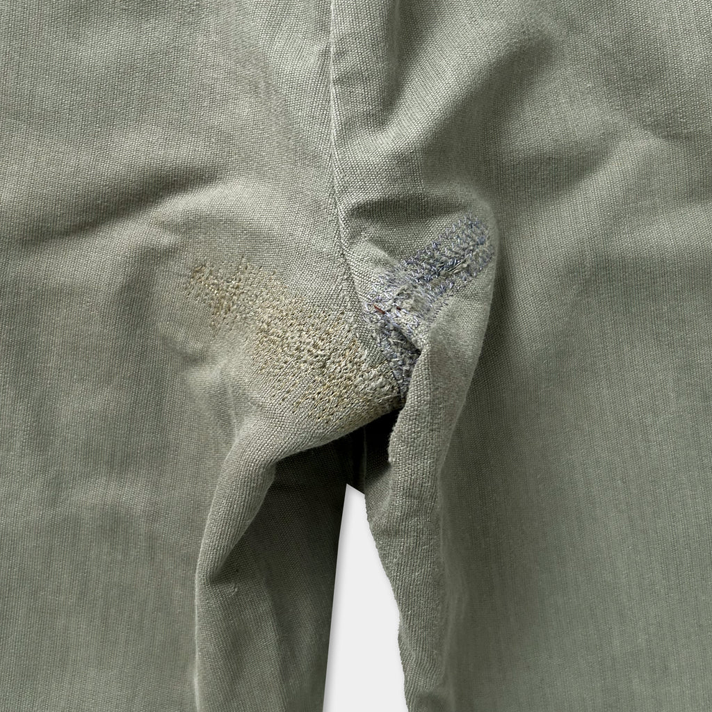 a close-up view of a pair of gray pants with a noticeable tear or rip in the fabric.